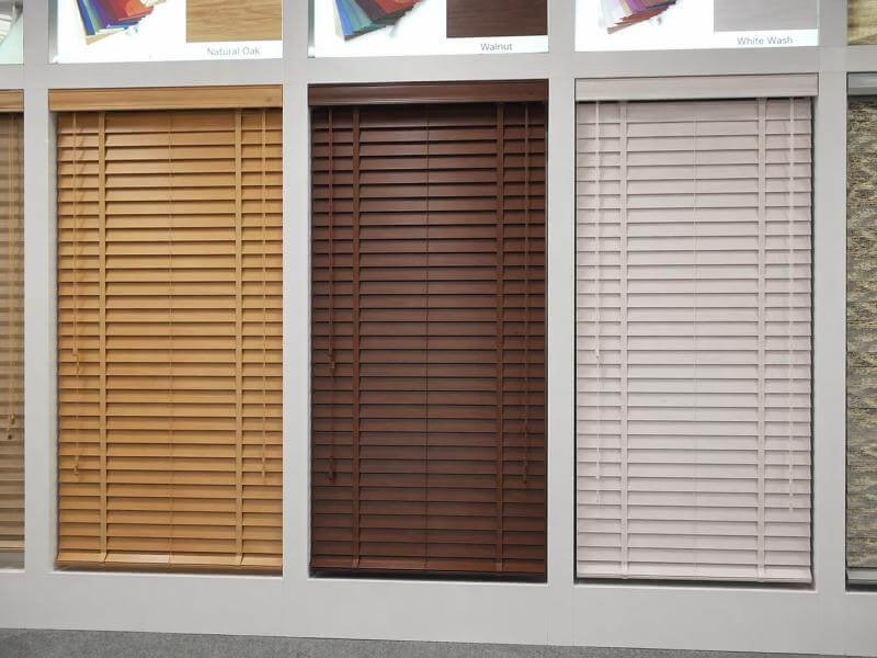 Wood venetian blinds in natural oak stain, walnut stain, and whitewash finishes side by side